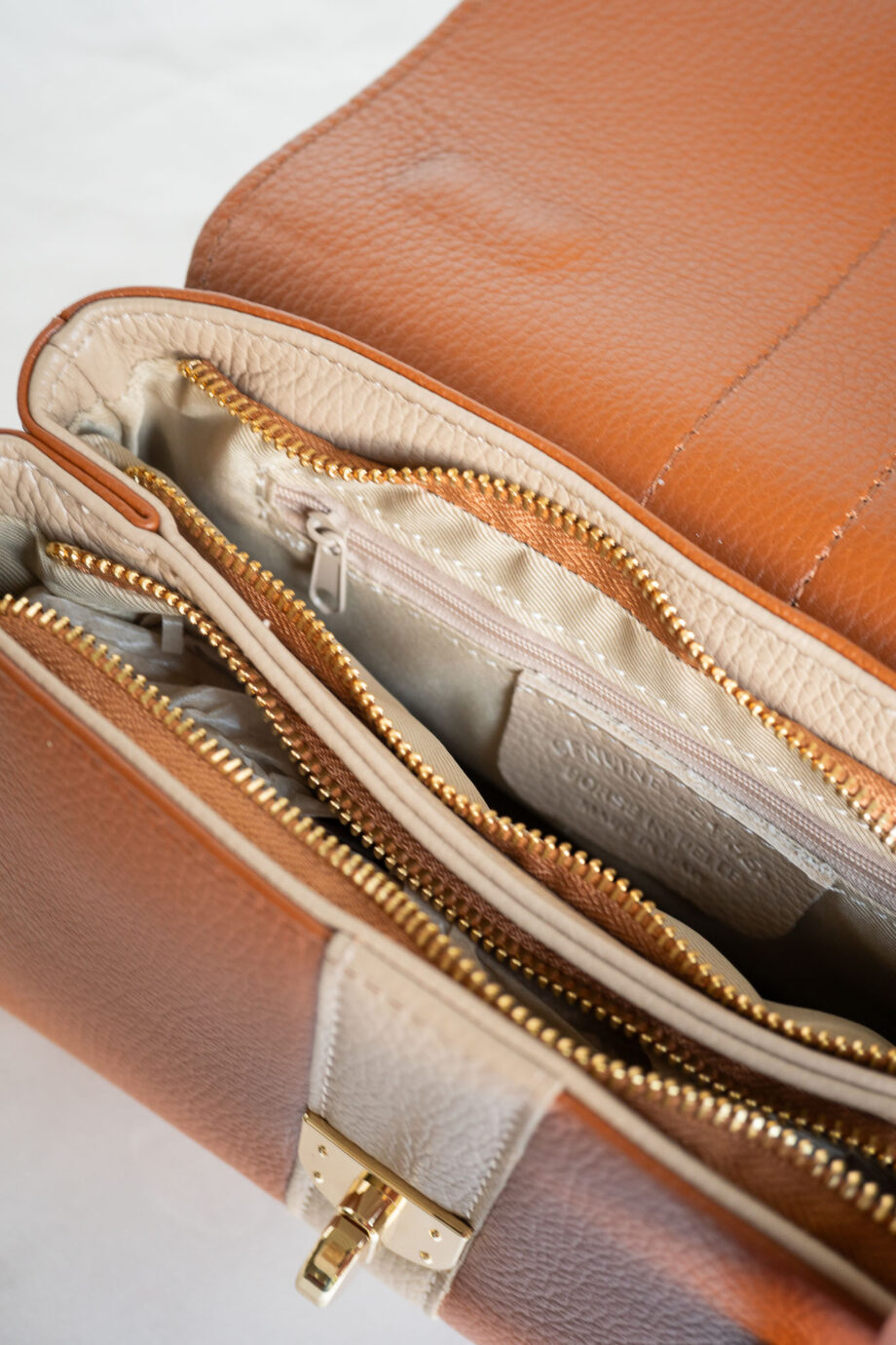 Deze stijlvolle leren handtas in een prachtige two-tone combinatie van cognac bruin en taupe beige is perfect voor elke gelegenheid. De tweekleurige dames schoudertas is voorzien van een chic streepdesign en heeft een verstelbaar leren hengsel in taupe, waardoor je hem gemakkelijk kunt dragen als schoudertas of crossbody bag