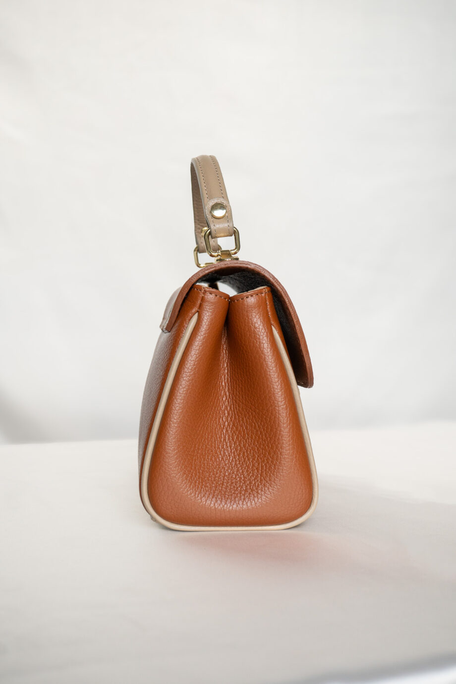 Deze stijlvolle leren handtas in een prachtige two-tone combinatie van cognac bruin en taupe beige is perfect voor elke gelegenheid. De tweekleurige dames schoudertas is voorzien van een chic streepdesign en heeft een verstelbaar leren hengsel in taupe, waardoor je hem gemakkelijk kunt dragen als schoudertas of crossbody bag